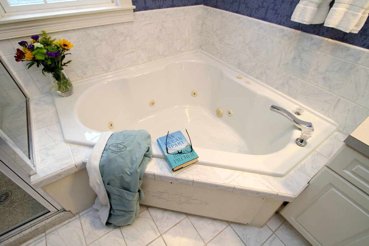 up close view of corner spa tub surrounded by white ceramic tiles
