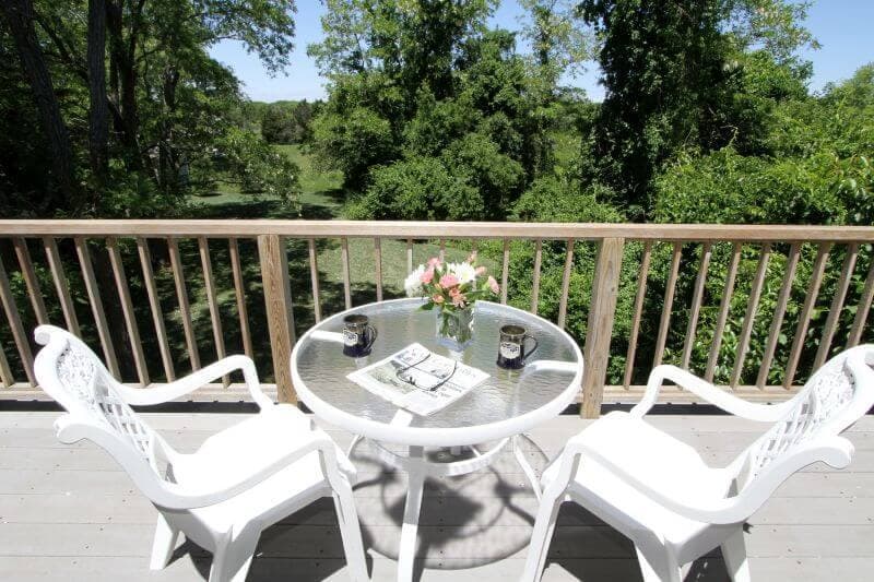 view of table and chairs on balcony area overlooking greenspace