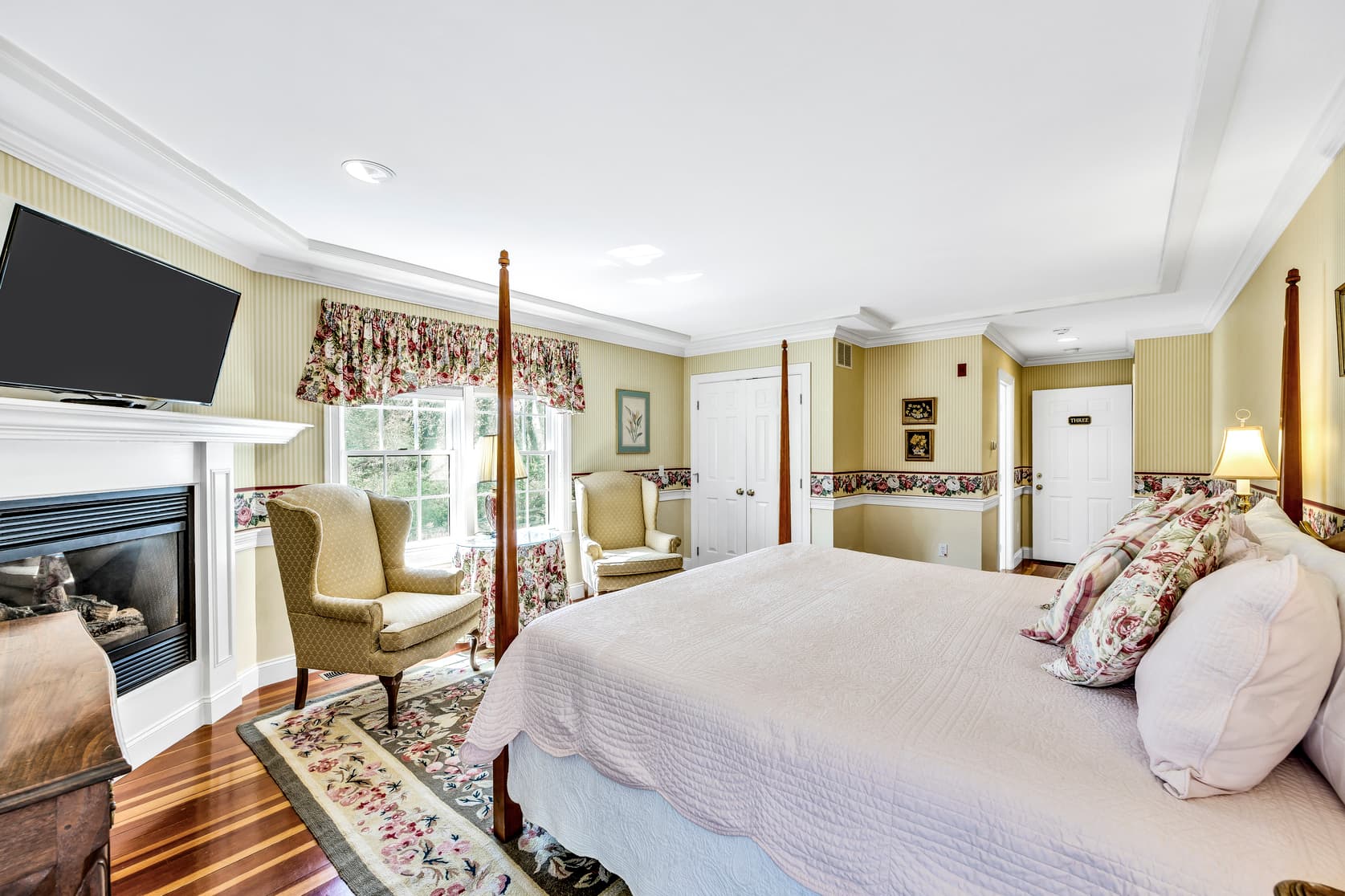 View of King bed, sitting area, fireplace, flatscreen TV, lamp and bedside table
