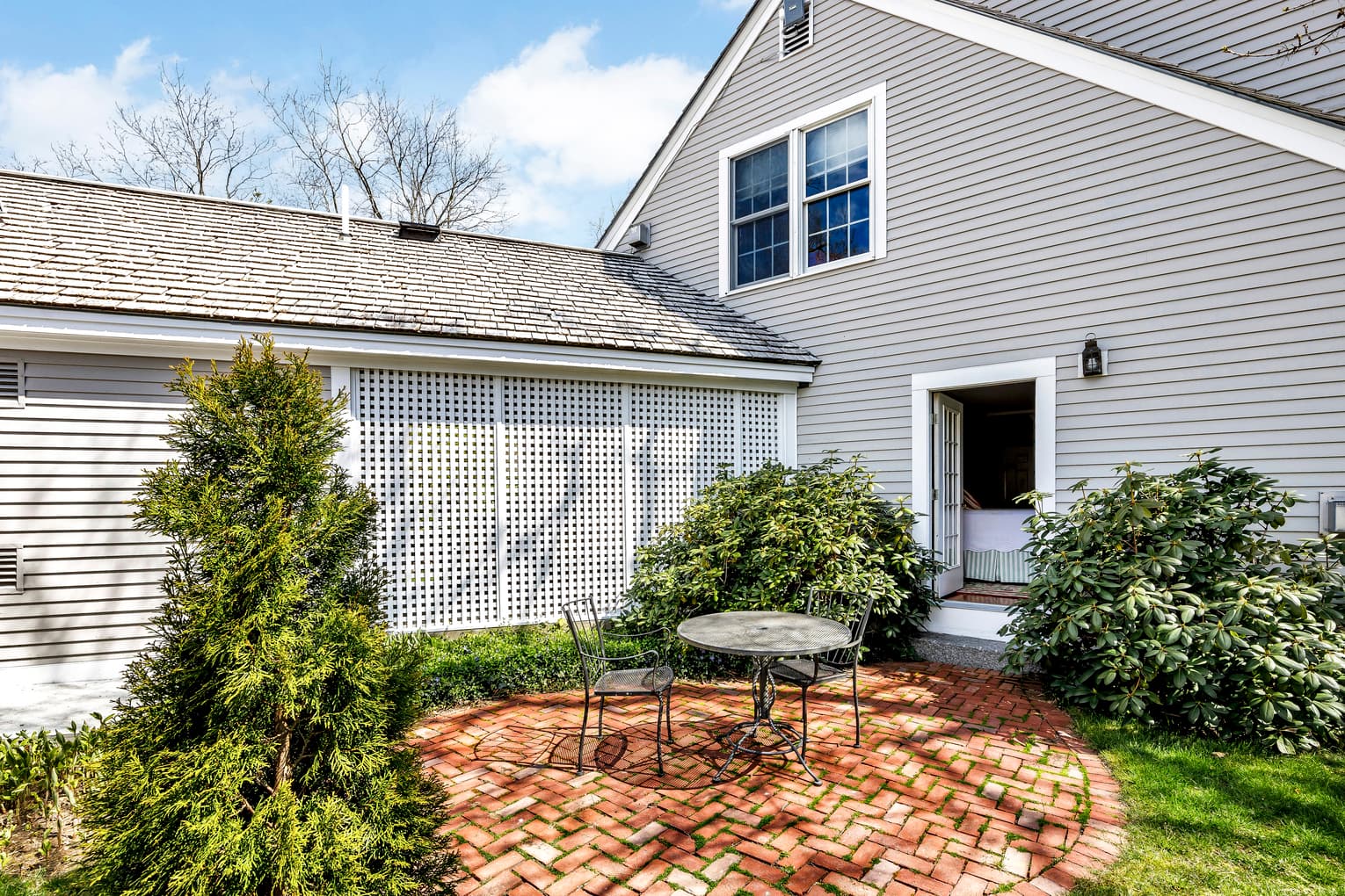 private patio area with red brick, loungers and screen separating patio on other sideshown