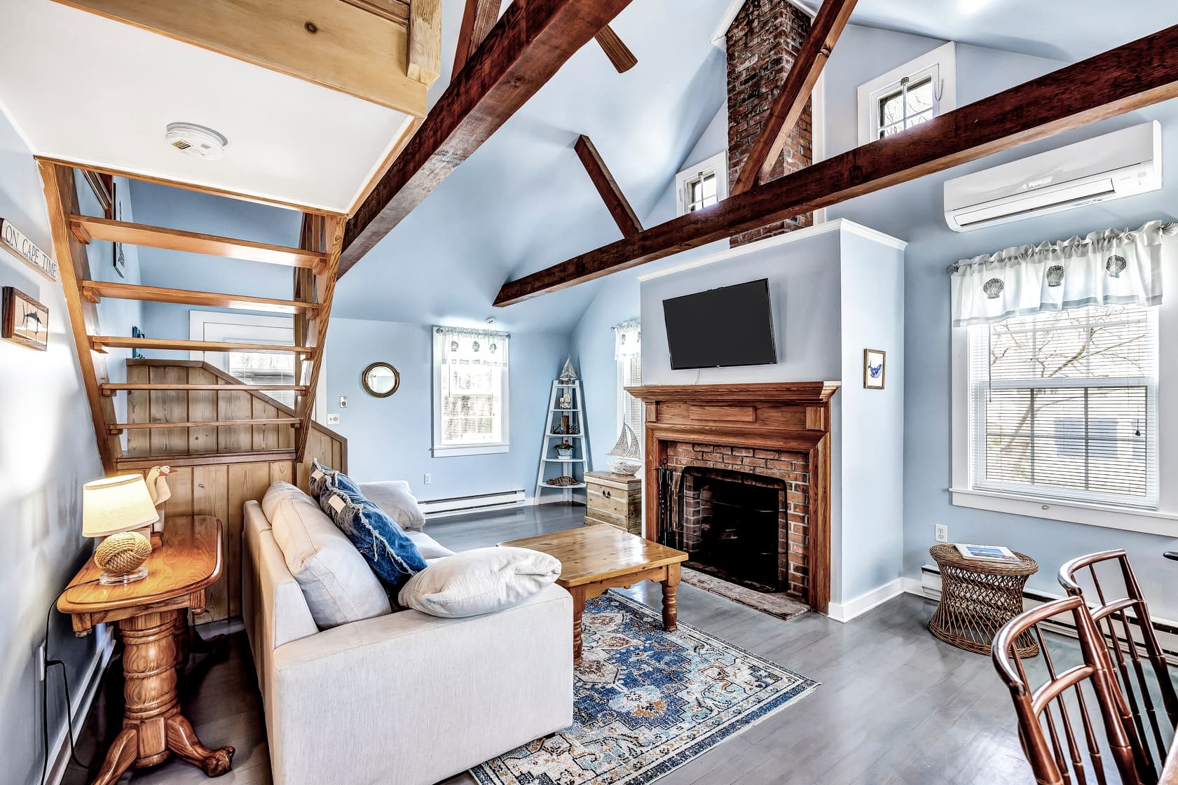 Queen size bed white wooden bed, with Laura Ashley blue and white bedding with blue, white yellow, decorative pillows, bedside tables and 2 bedside lamps, gray wooden floors