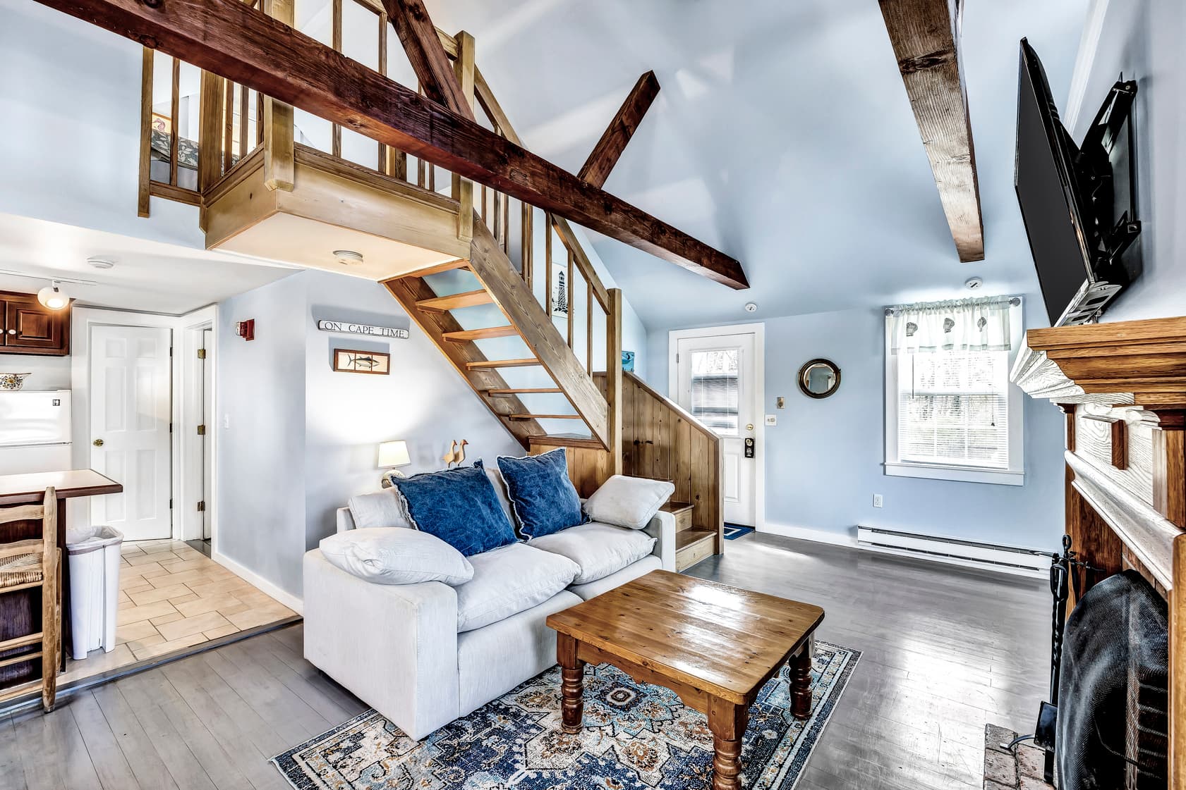 twin beds in loft area with slanted ceilings, blue and white bedding, one bedside table with lamp, beige carpet