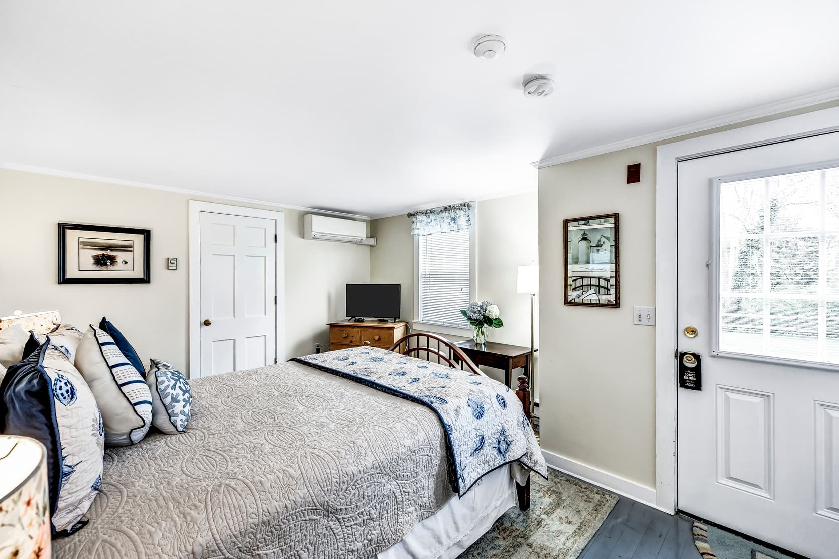 queen bed with coastal decor pillows, ductless A/C, main door, flatscreen TV