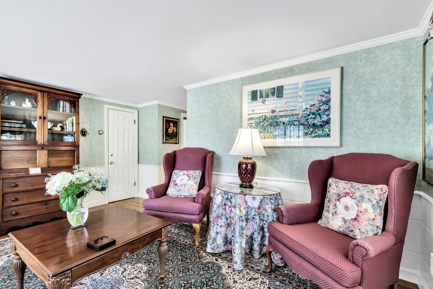 close up of white soaking tub, surrounded by white ceramic tile, white with pink roses wallpaper border and light pink walls