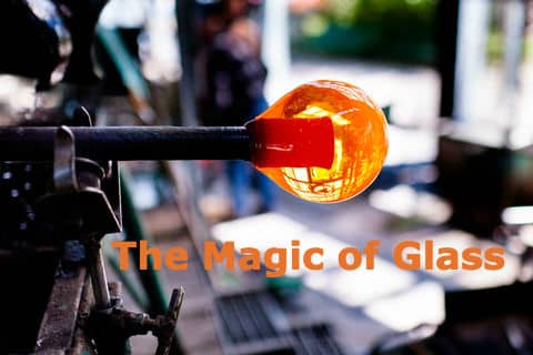 A glowing orange glass bubble forming on a blowing pipe in a glassblowing workshop.