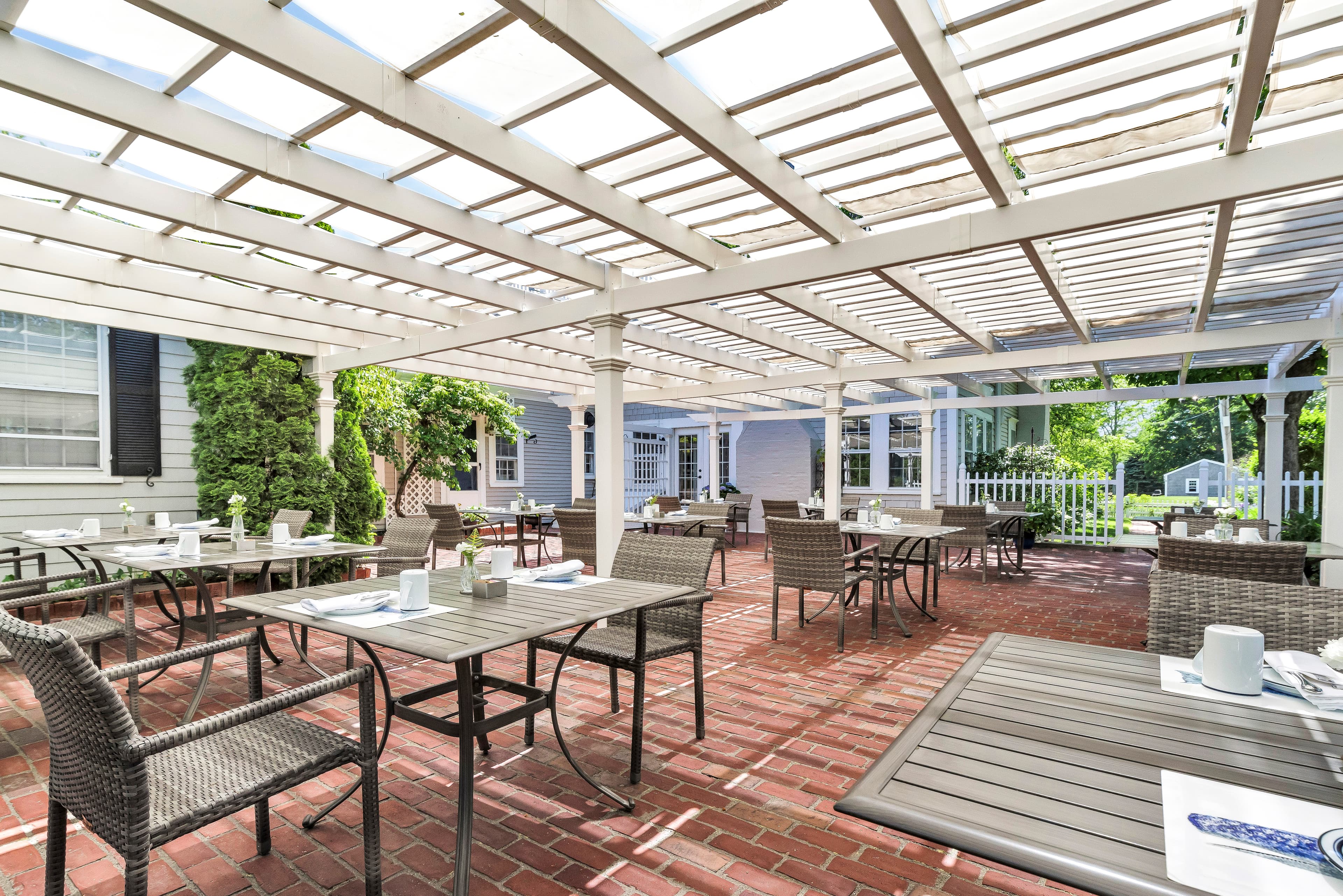 Outdoor dining area with tables and chairs under a pergola.