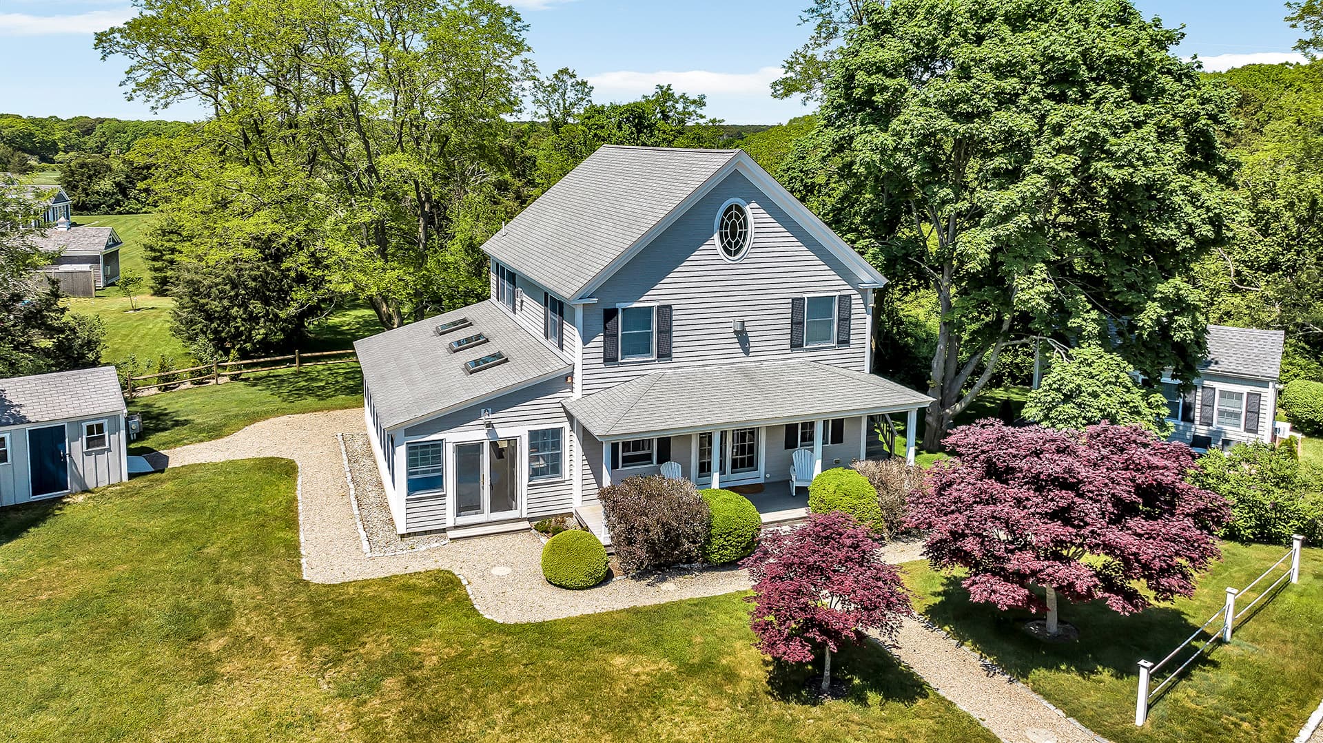 Aerial view of a charming two-story house surrounded by greenery and decorative shrubs.