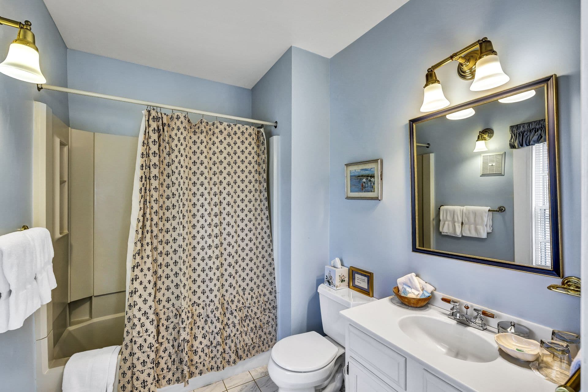 private bathroom with shower/tub combo, toilet and sink with mirror and light scones above