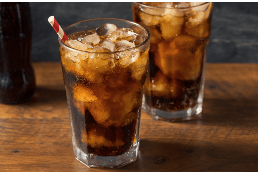 Two glasses of cola with ice and a striped straw on a wooden surface.