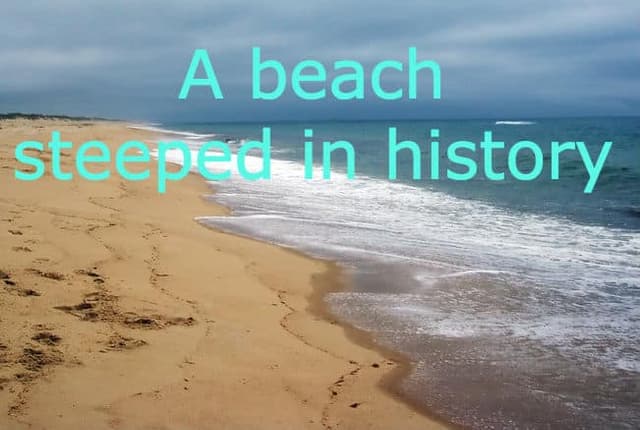 A sandy beach with gentle waves under a cloudy sky.
