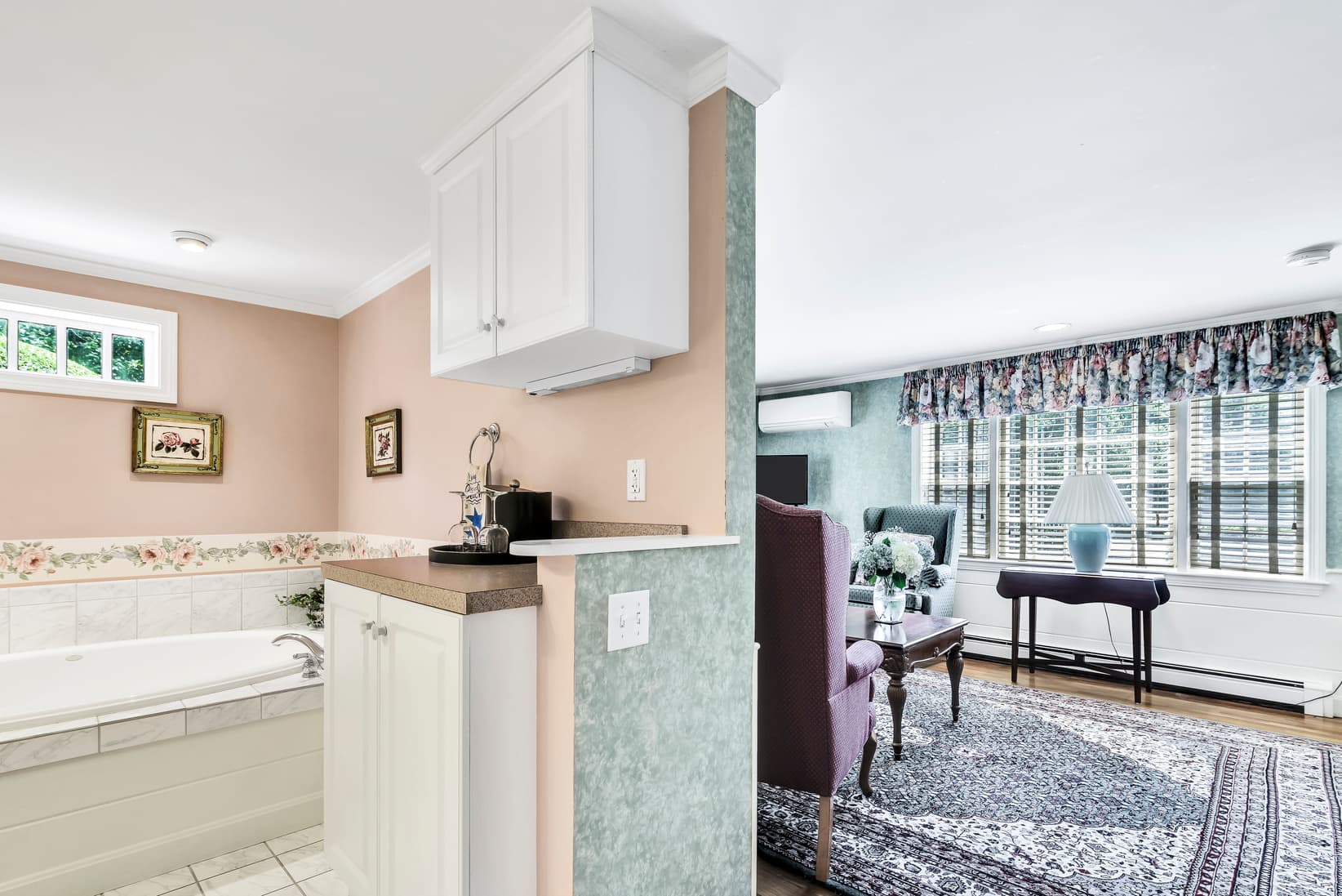 A bright, open space featuring a bathroom with a tub and an adjacent living area with floral decor.