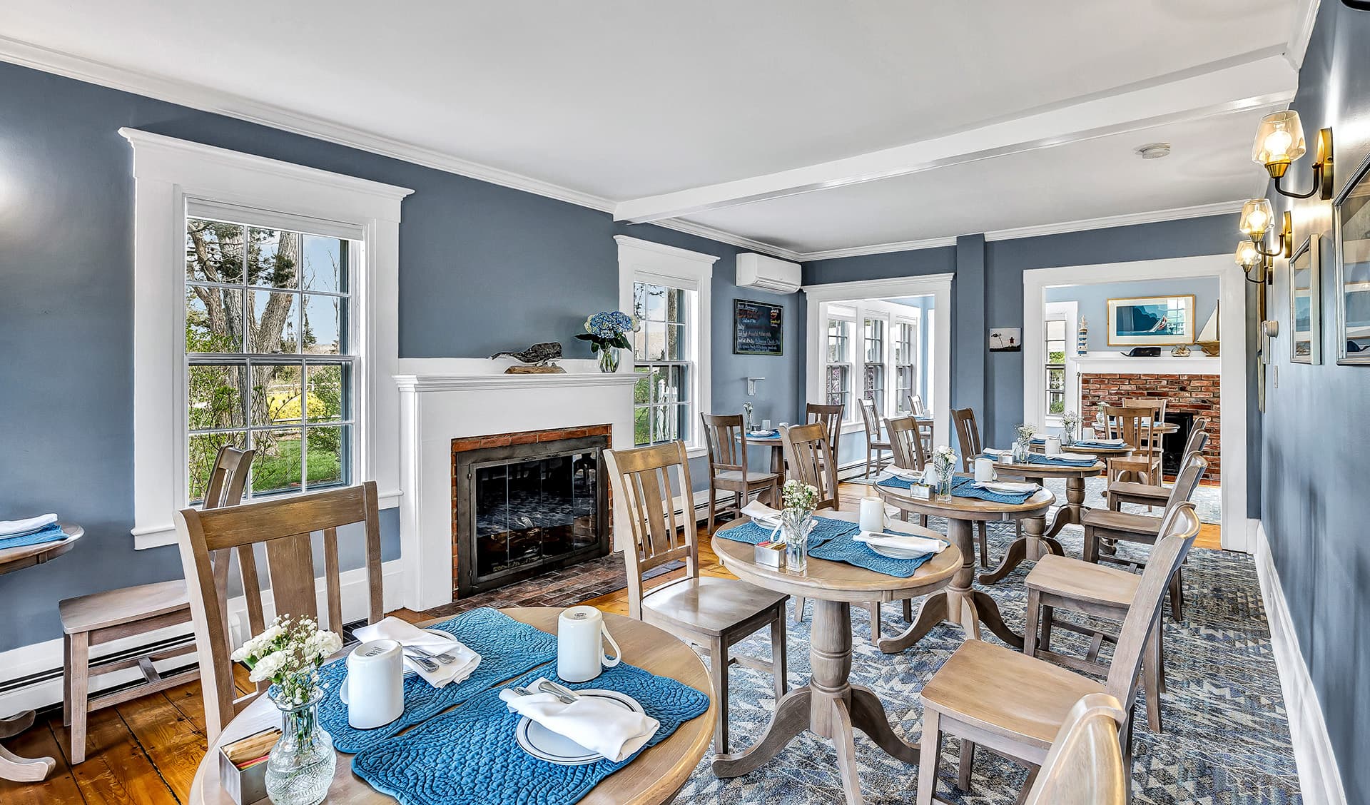 Bright and inviting dining room with wooden tables, blue decor, and large windows.