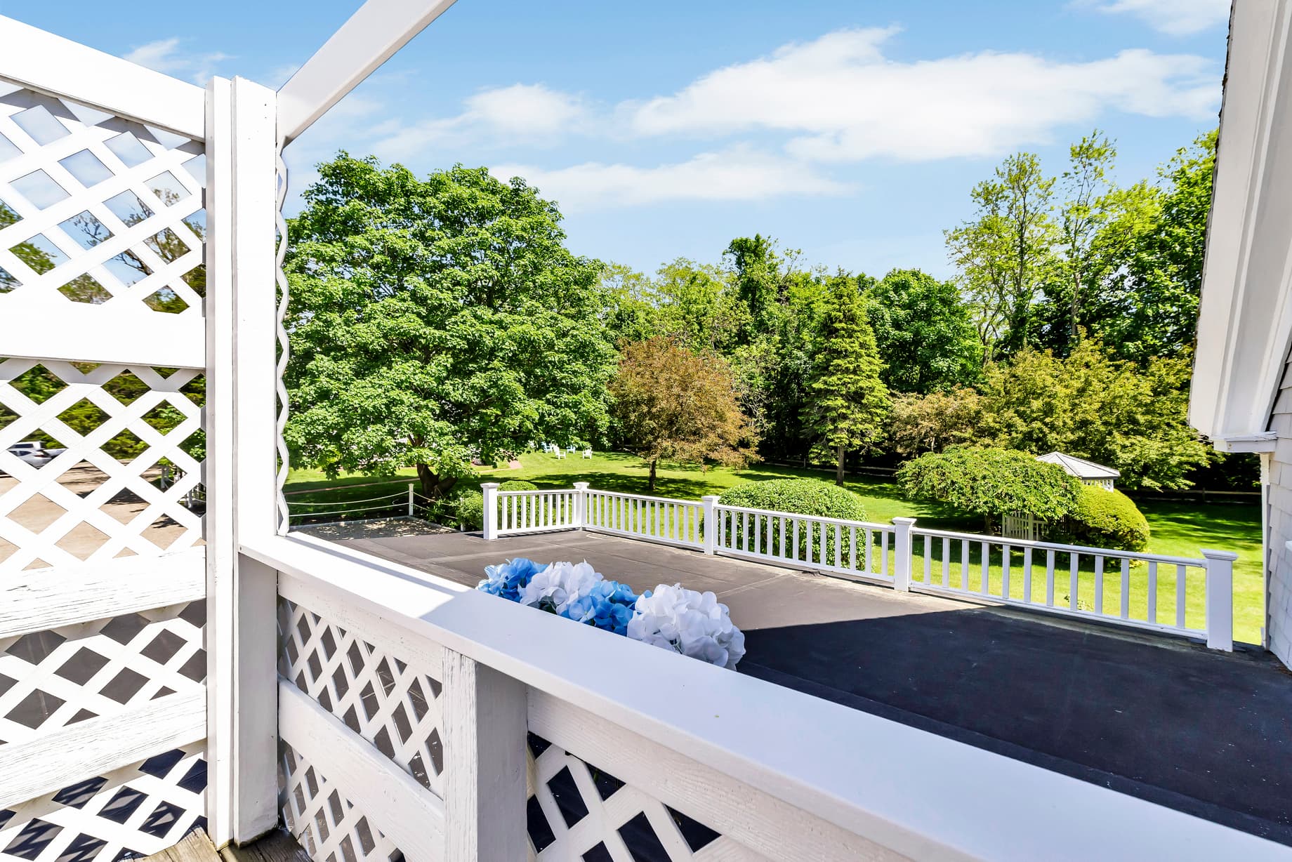 View from a balcony overlooking a lush green landscape and yard.
