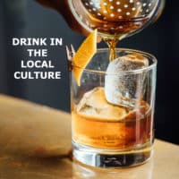 Closeup photo of a filled cocktail glass with title: Drink in the local culture.