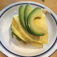 Photo of breakfast sandwich topped with avocado slices.