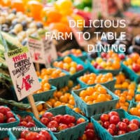 Baskets of multi-colored cherry tomatoes, stacks of leeks and other fresh veggies with a sign that says "organic fresh cherry tomatoes."